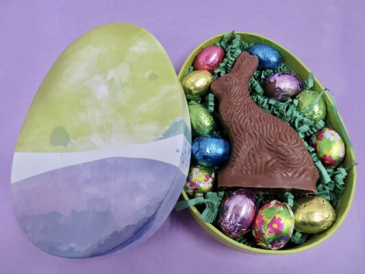 Egg shaped box packed with Easter grass and goodies