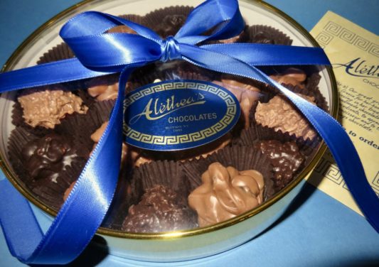round gold gift box of gourmet chocolate clusters